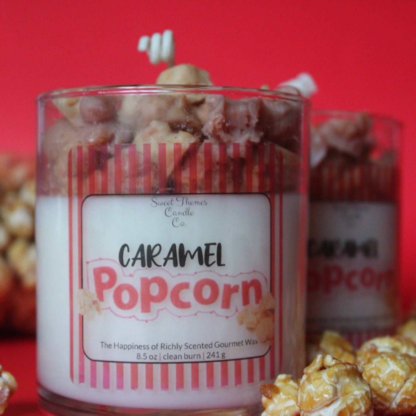 Candle labeled 'Caramel Popcorn' with waxed popcorn on a red background