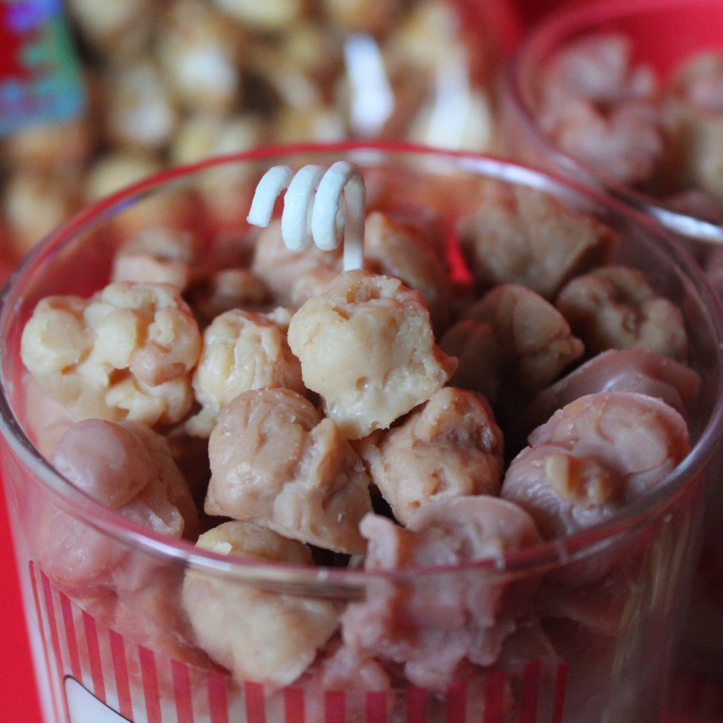 Clear container filled with waxed popcorn embeds on a red background