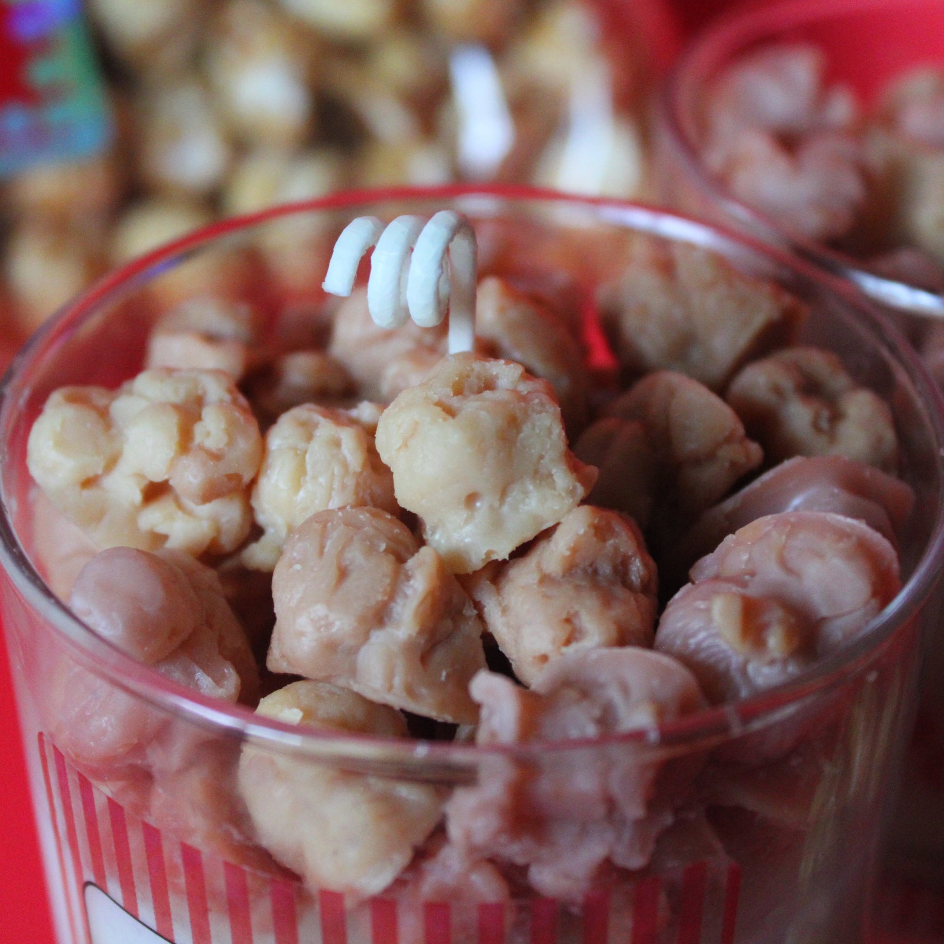 Clear container filled with waxed popcorn embeds on a red background