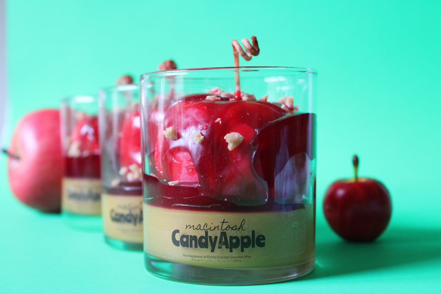 Candy apple-themed candles with red apples on a green background