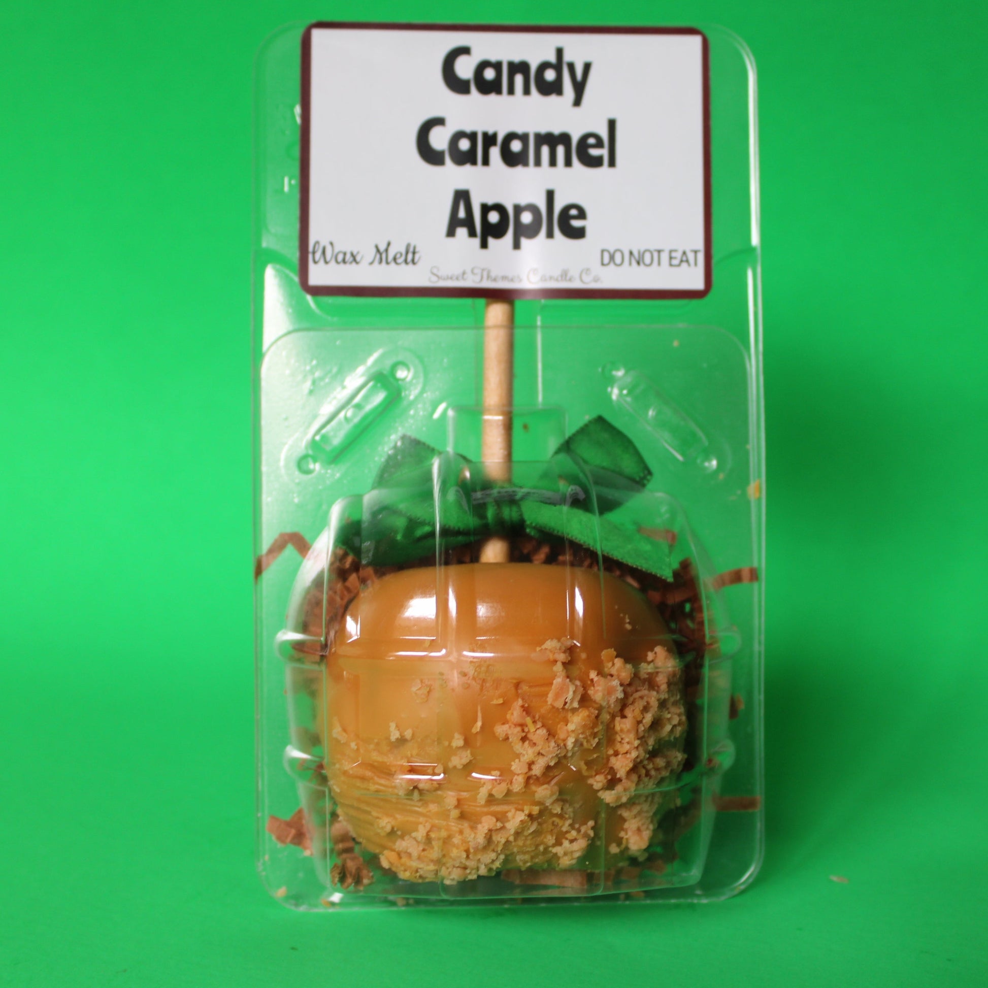 Candy caramel apple in packaging with a label on a green background